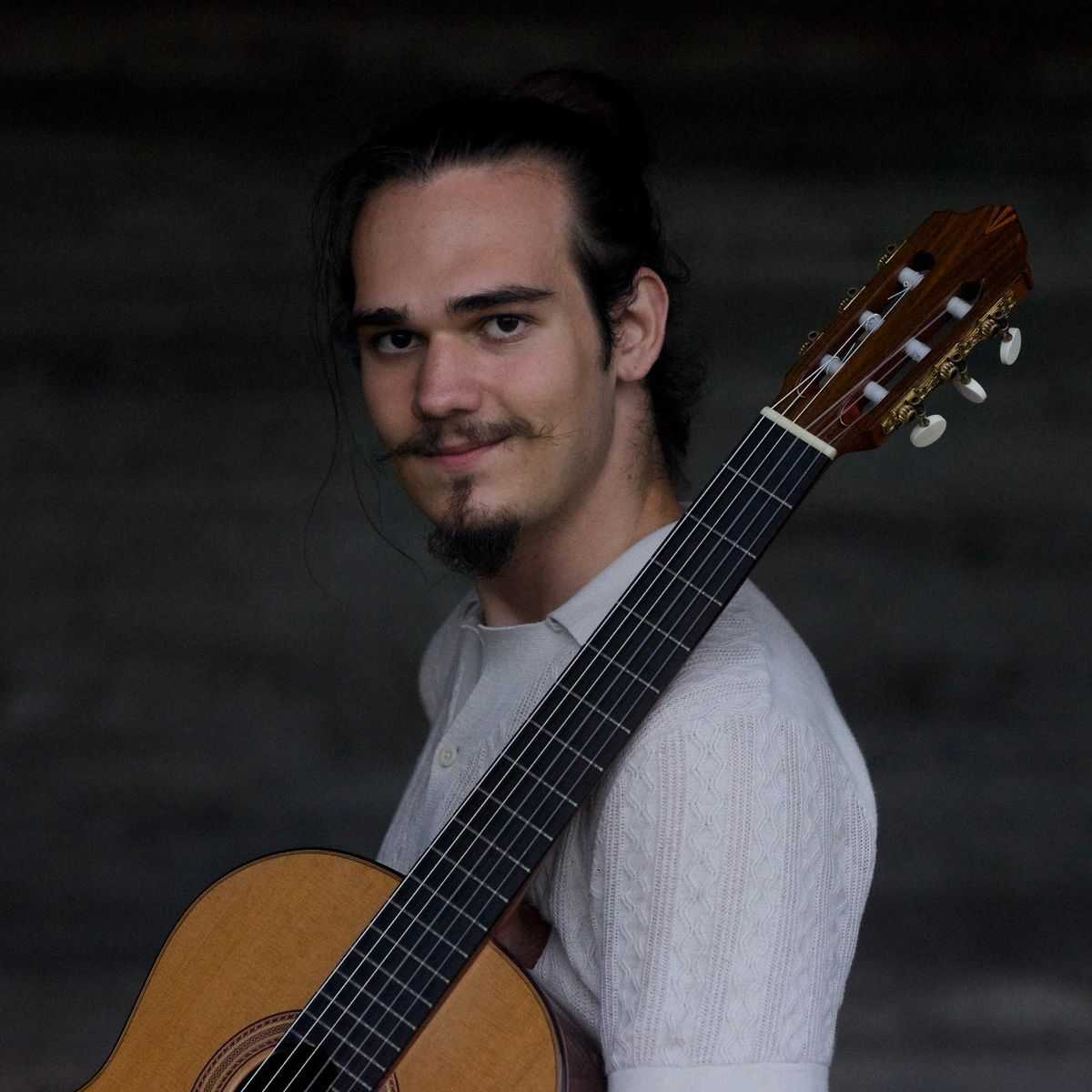 Viktor in front of his guitar with a soft smile.
